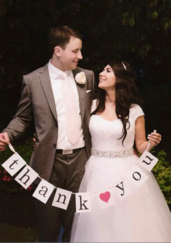 The Simonetti's holding a thank-you banner on their wedding day