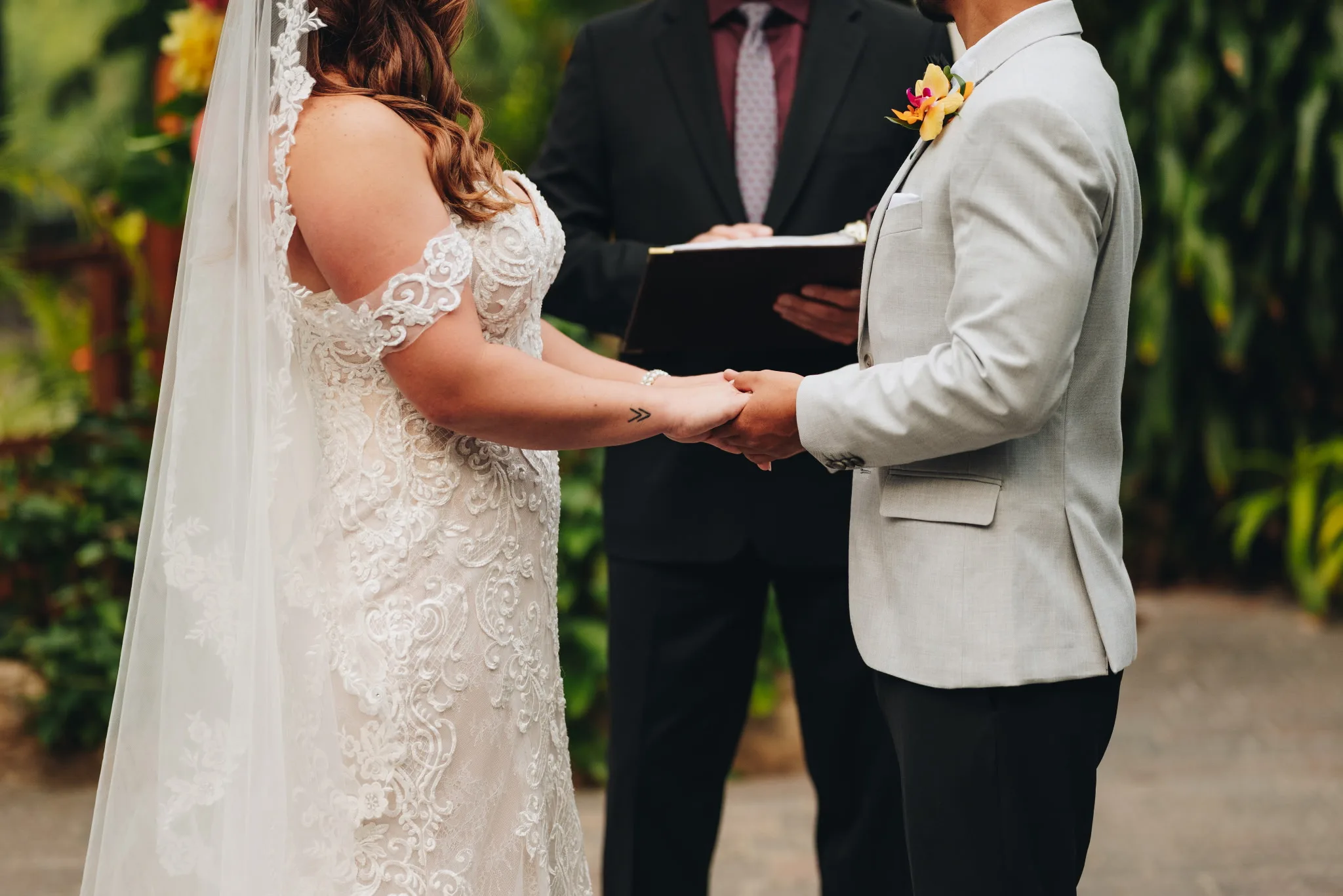 A bride and groom holding hands as Jeff McQueen officiates their vows